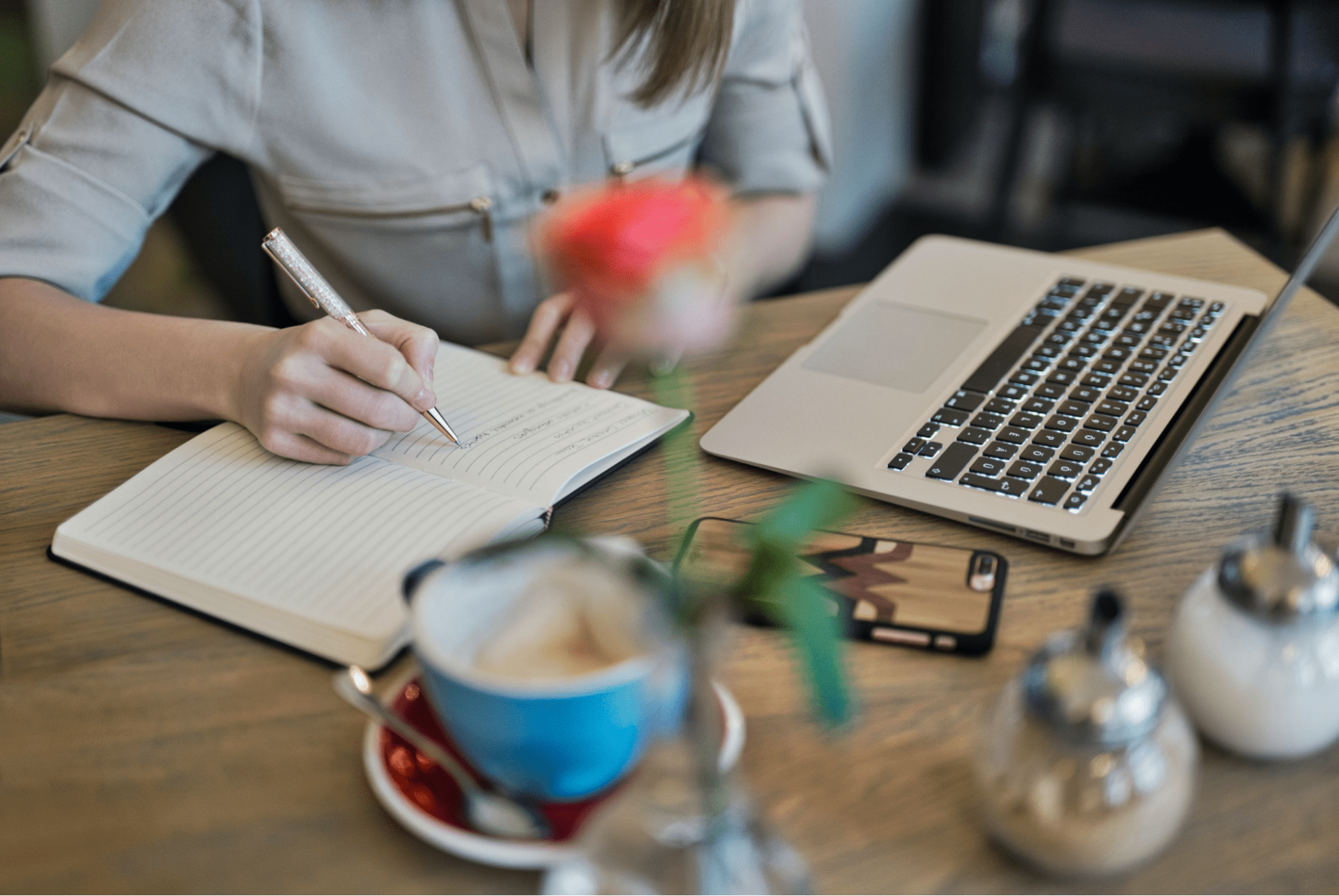 A woman taking notes from a video on her laptop