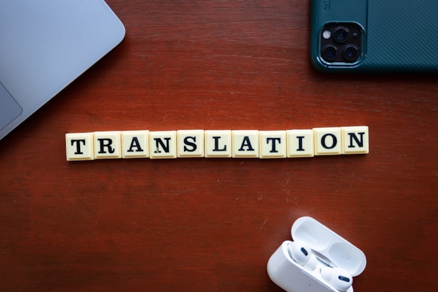 机の上に置かれた木製ブロックで「TRANSLATION」とつづられ、翻訳や語学学習の重要性を象徴するコンセプトフォト