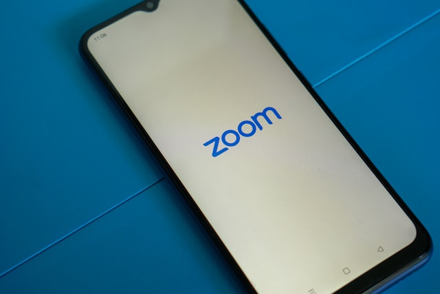 Zoomのロゴが表示されたスマートフォンの起動画面。モバイルアプリを使ってZoom会議や画面共有を行う手順の説明に使用できるシンプルな写真。