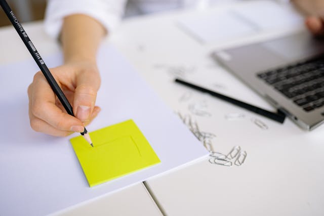 付箋にアイデアを描きながら作業する人の手元とノートパソコン