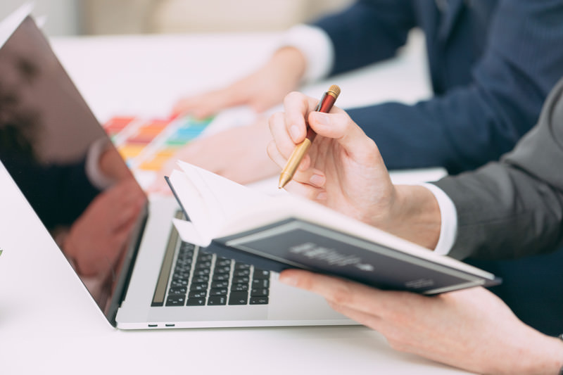 会議中にノートへメモを取るビジネスパーソン