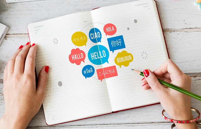 ノートに「Hello」「Hallo」「こんにちは」など多言語のあいさつが吹き出しで描かれている写真。翻訳アプリや語学学習のイメージに最適です。
