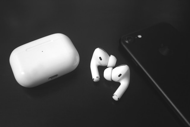 黒いiPhoneのそばに置かれたAirPods Pro 3のイヤホンと充電ケース。高級感あるブラック背景に映え、最新モデルのデザインが際立つ