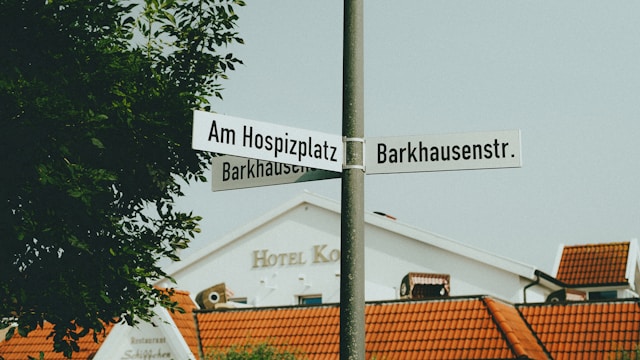 道路の角に立つ標識に外国語の通り名が表示されている。旅行者がデンマーク語の地名や案内を翻訳アプリで確認しながら街を散策するシーンを想像させます。