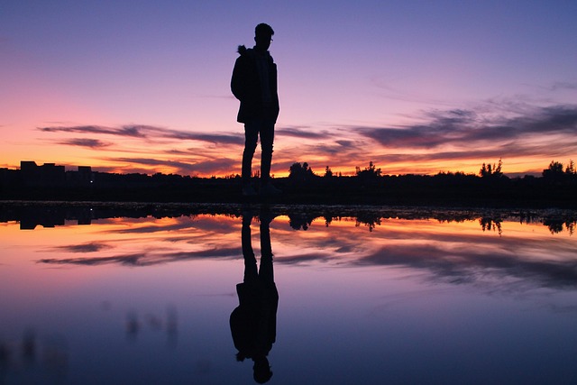夕焼け空を背景に静かな水面に人物のシルエットが映り込んでいる写真。Nano Banana Proの生成する幻想的な光の表現や反射の美しさを連想させる。
