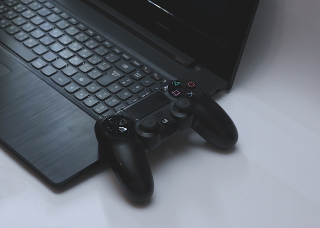 黒いノートパソコンの上に置かれたPlayStation風ゲームパッド。PCとゲームコントローラーを接続してPCゲームやコンソールゲームを録画するスタイルを示す。