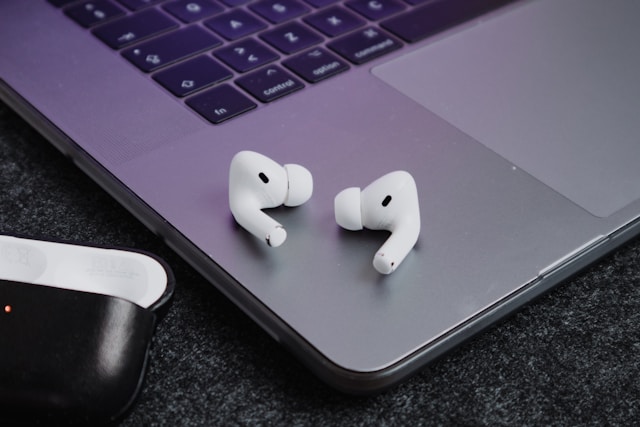 MacBookのキーボードの横に置かれたAirPods Pro 3のイヤホン。PC作業と併用するシチュエーションを表現