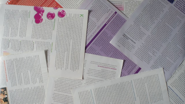 散らばった英語論文の印刷物。PDFをOCRで翻訳する必要に迫られている場面。