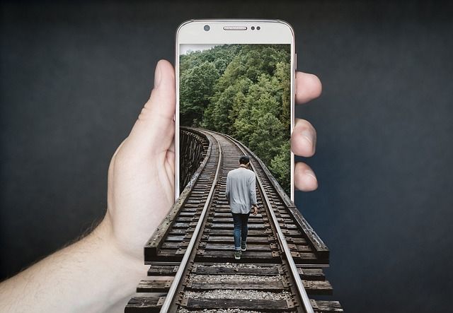 スマホ画面から線路が続く合成イメージ｜DALL-E 3で作れる超現実的な画像生成の例
