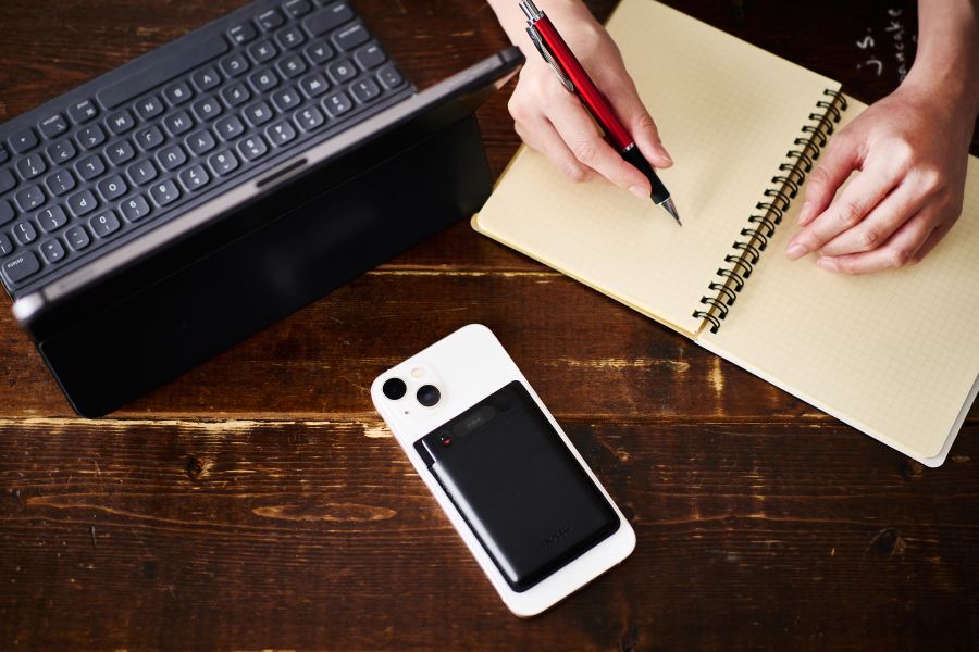 木製のデスクの上にパソコンとノートとともに、Notta Memoが搭載されたスマホ。画面を操作しなくても録音が可能。