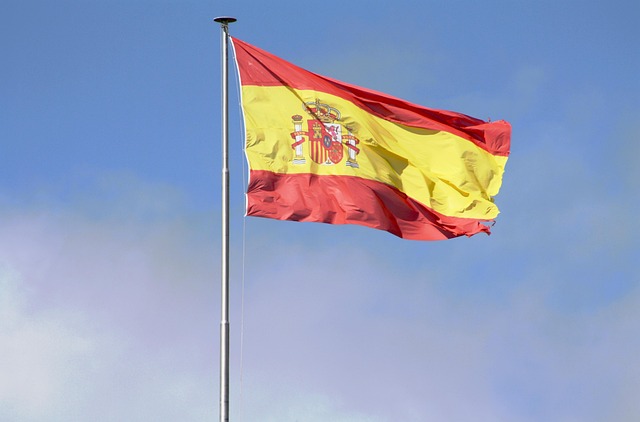 青空に掲げられたスペインの国旗。スペイン語翻訳サービスの必要性を表す視覚的な写真です。