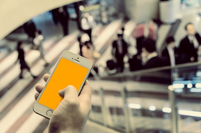 駅や空港など人が行き交う場所でスマートフォンを手にする旅行者。翻訳アプリでウルドゥー語の案内を読み取り、移動をスムーズにする場面を表現。