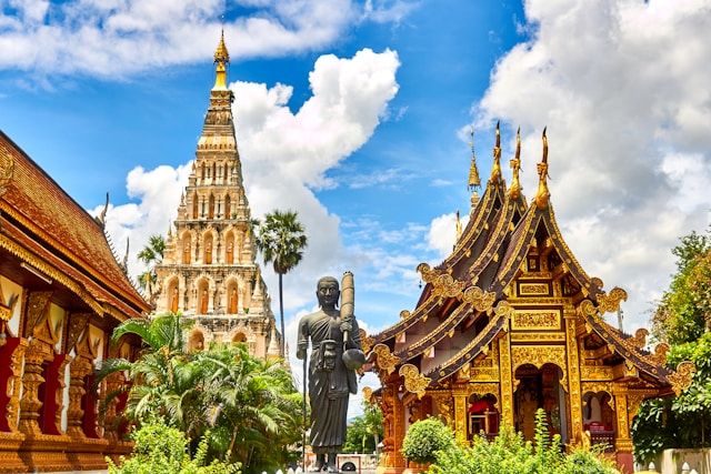 金色に輝く寺院と仏塔が並ぶ、タイの伝統的な建築物。タイ旅行で翻訳アプリを使い、現地の寺院案内を理解するイメージ。