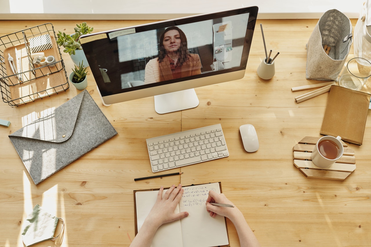 persoon die deelneemt aan een online vergadering en op een notitieboek schrijft